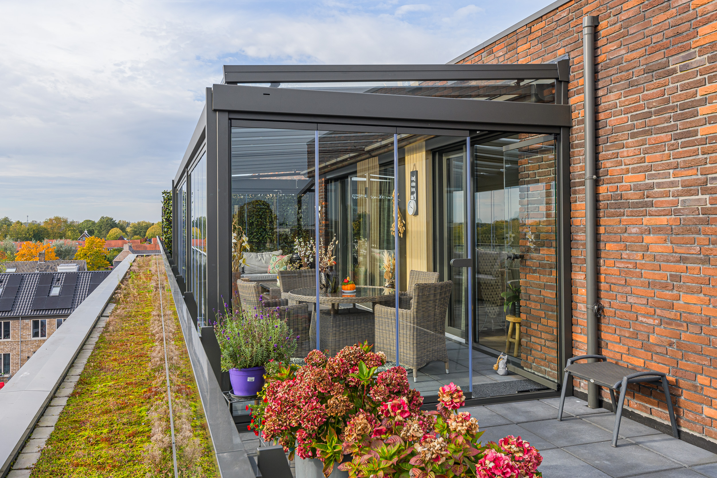 Buitenaanzicht van glazen balkonbeglazing met schuifwanden, aluminium frame en planten op het balkon bij een appartement