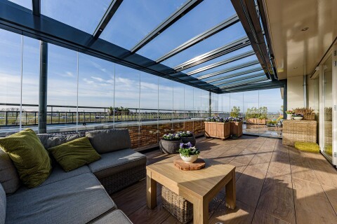 Groot balkon met glazen schuifwanden en stijlvolle inrichting voor optimaal comfort.
